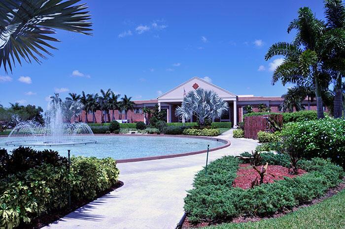 A view of a grassy courtyard between two multi-story apartment buildings with palm trees — 287 Suffolk G, Boca Raton FL 33434, BOCA RATON, FL