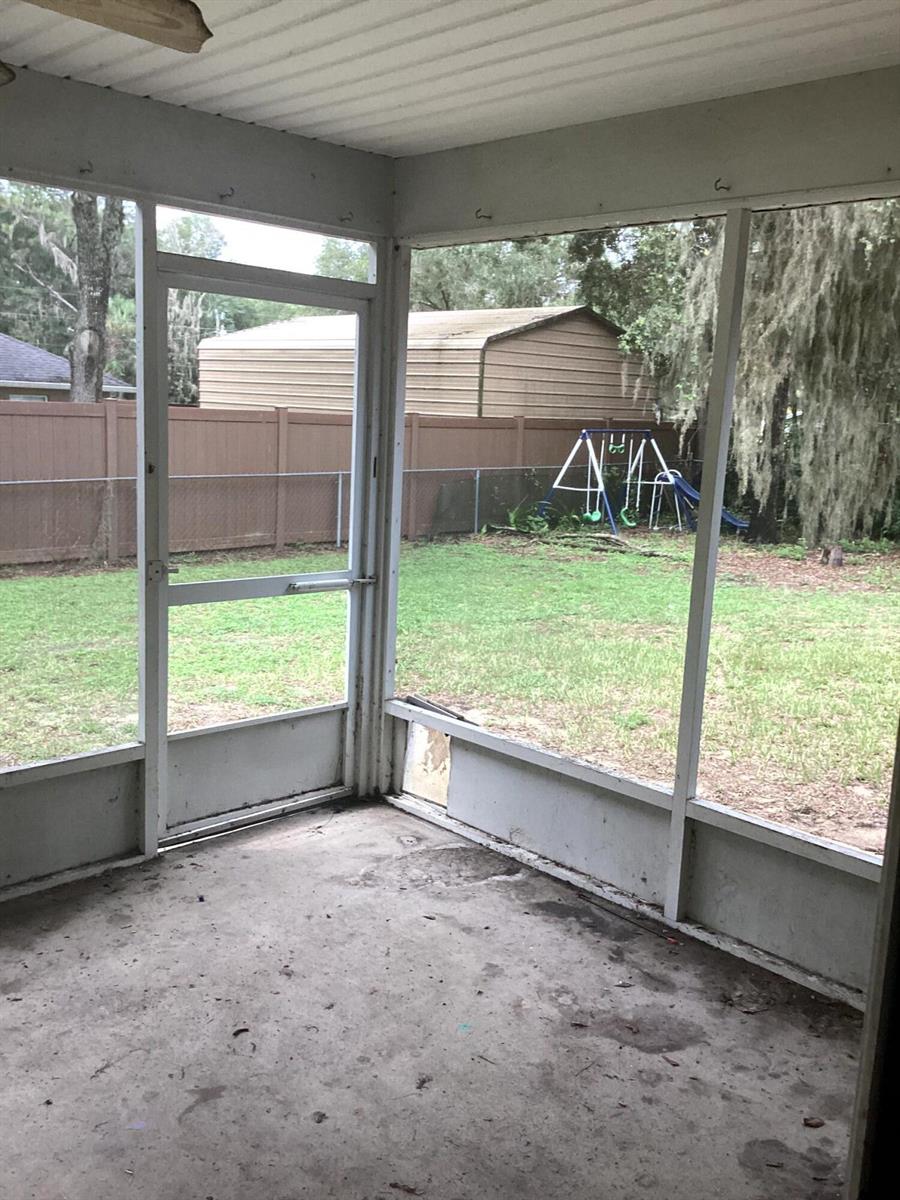 A screened-in porch with a concrete floor, a screen door, and a view of a backyard — 11880 SE 195th Place, FL 34431, FL