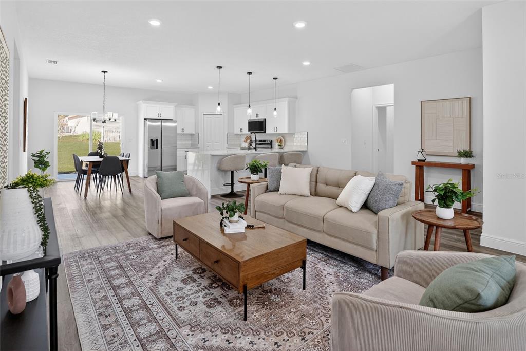 An open-concept living room and kitchen feature light wood flooring, neutral furniture, and recessed lighting — 9129 N ANTON WAY, CITRUS SPRINGS, FL