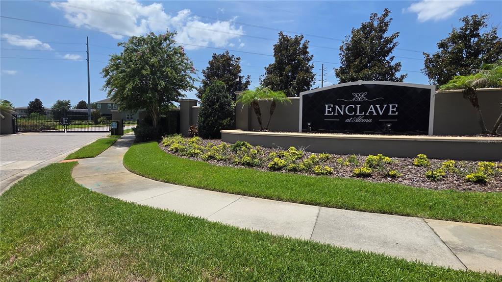 The entrance to a residential community features a sign reading Enclave at Aloma — 8104 PLEASANT PINE CIRCLE, WINTER PARK, FL