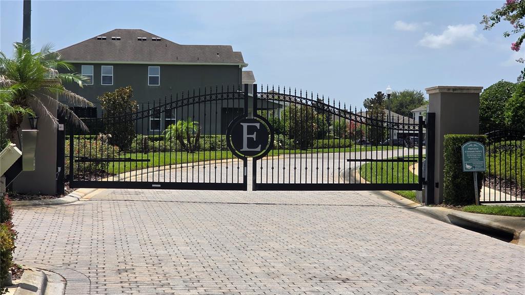 A black metal gate with a central letter E stands at the entrance of a community — 8104 PLEASANT PINE CIRCLE, WINTER PARK, FL