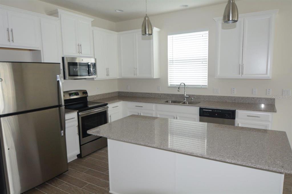 A kitchen with white cabinets, stainless steel appliances, and a granite-topped island — 8104 PLEASANT PINE CIRCLE, WINTER PARK, FL