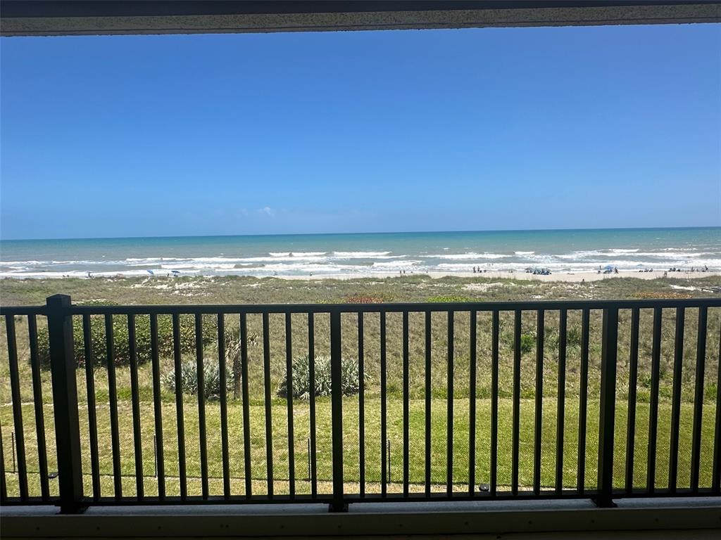 A balcony with a dark metal railing overlooks a grassy lawn and the ocean beach — 1890 N ATLANTIC AVENUE UNIT A403, COCOA BEACH, FL