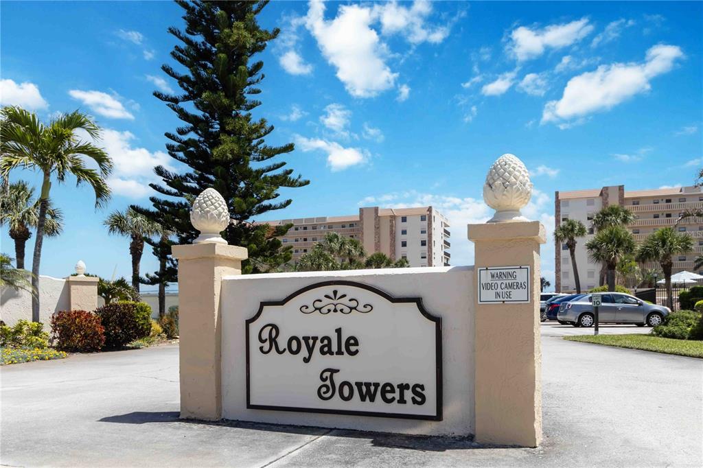 A sign for Royale Towers stands at the entrance to a residential complex with palm trees — 1890 N ATLANTIC AVENUE UNIT A403, COCOA BEACH, FL