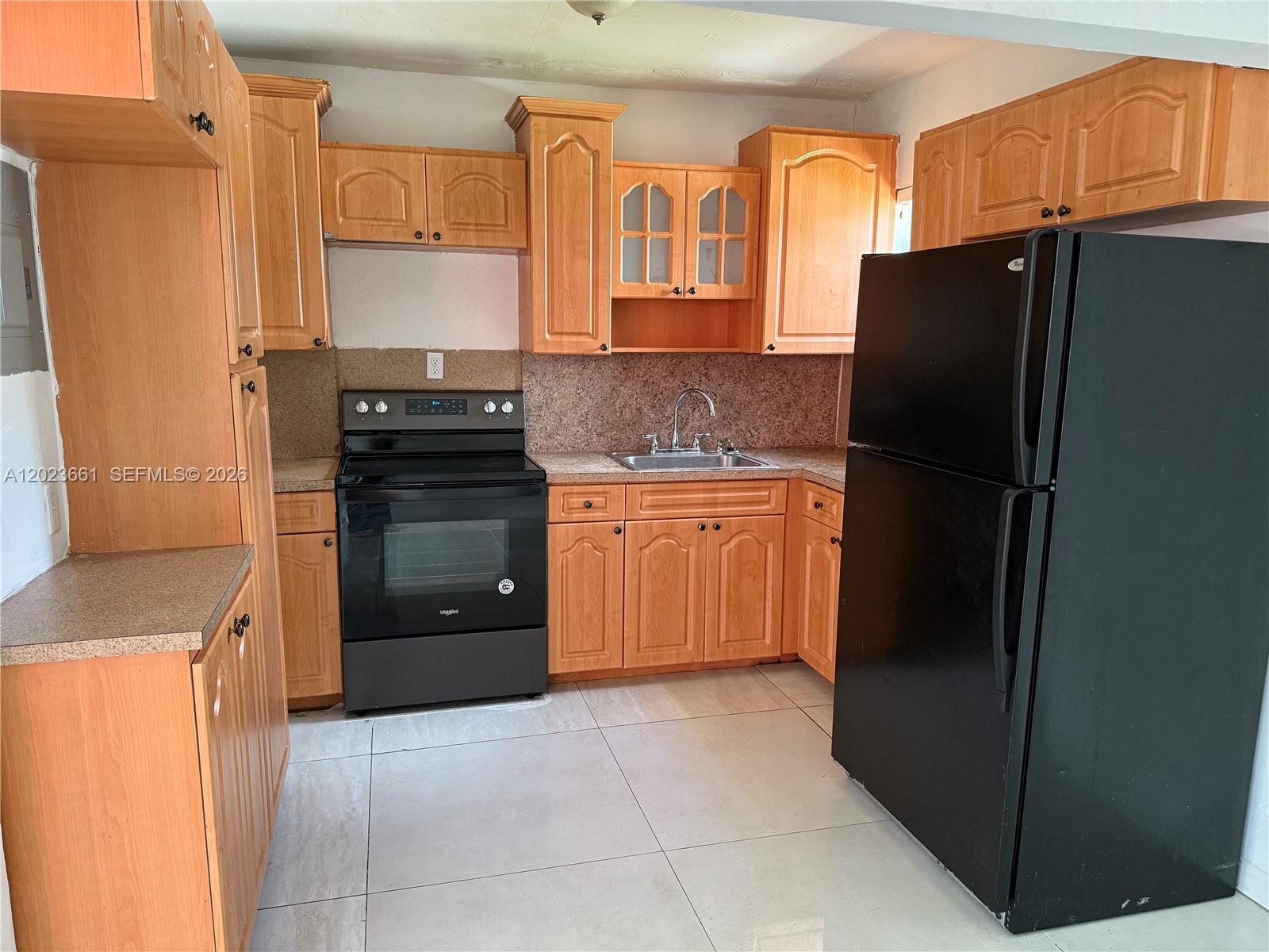 A kitchen features light wood cabinets, black appliances, a stainless steel sink, and tile flooring — 3810 SW 25th St # 1, West Park FL 33023, WEST PARK, FL