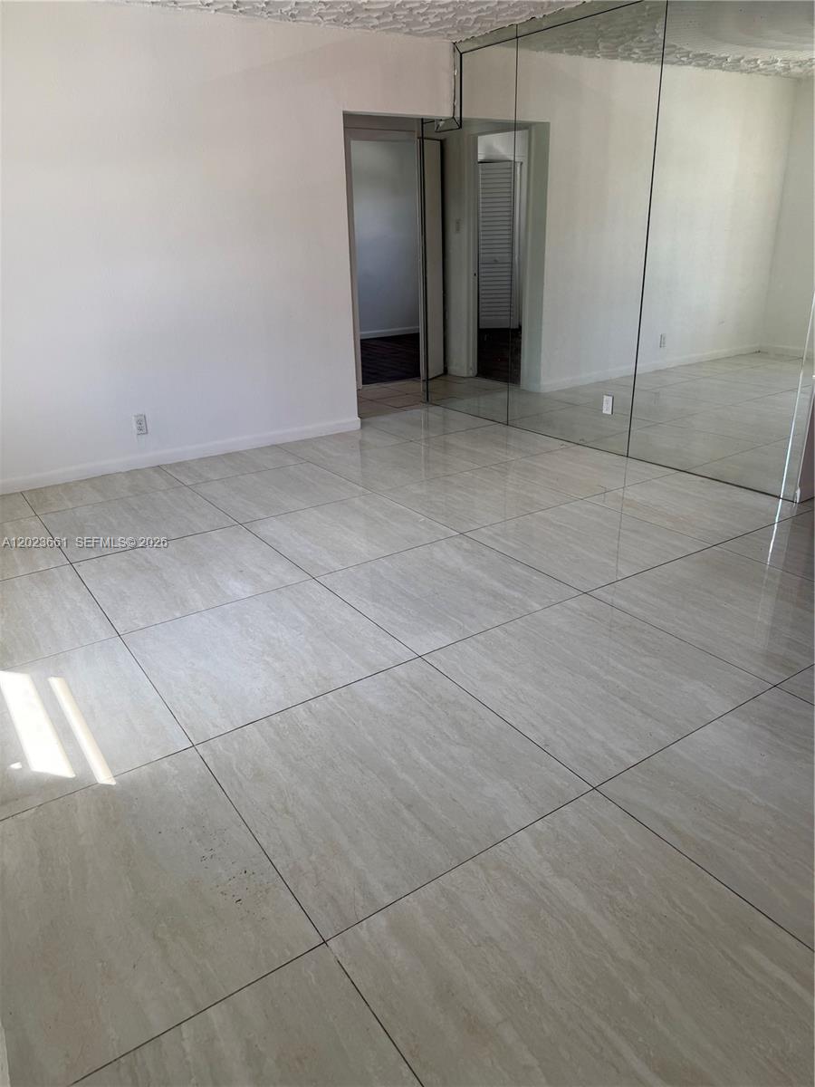 A room with large light-colored floor tiles, white walls, and a mirrored wall — 3810 SW 25th St # 1, West Park FL 33023, WEST PARK, FL