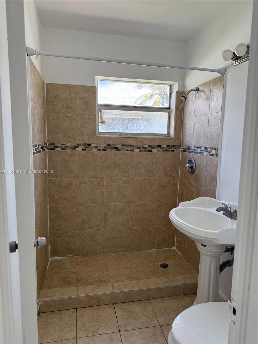 A small bathroom features a tiled walk-in shower, a pedestal sink, and a window — 3810 SW 25th St # 1, West Park FL 33023, WEST PARK, FL