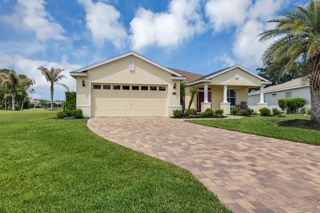 A single-story house with a beige stucco exterior, a paved driveway, and a front porch — 4334 BENT CREEK LANE, LEESBURG, FL