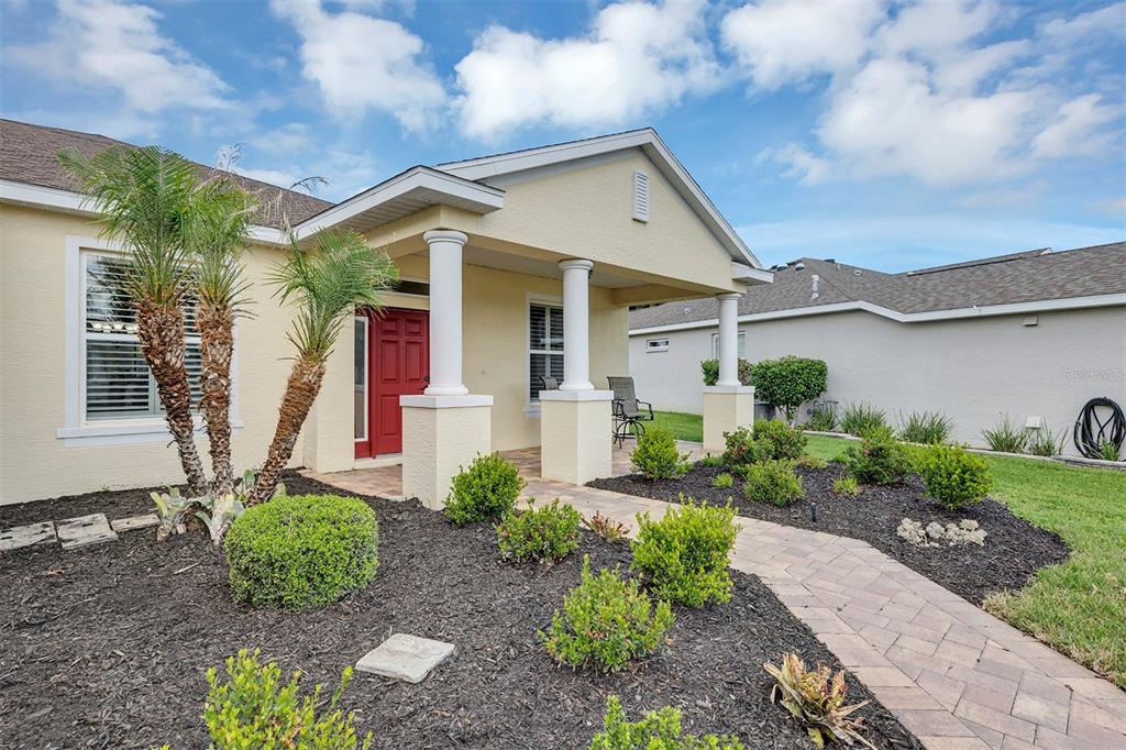 The exterior of a single-story house features a red front door, a covered porch, and landscaping — 4334 BENT CREEK LANE, LEESBURG, FL