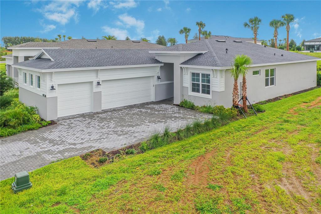 A single-story house with a gray shingled roof, white siding, and a paved driveway — 1618 BELLAGIO LOOP, TAVARES, FL