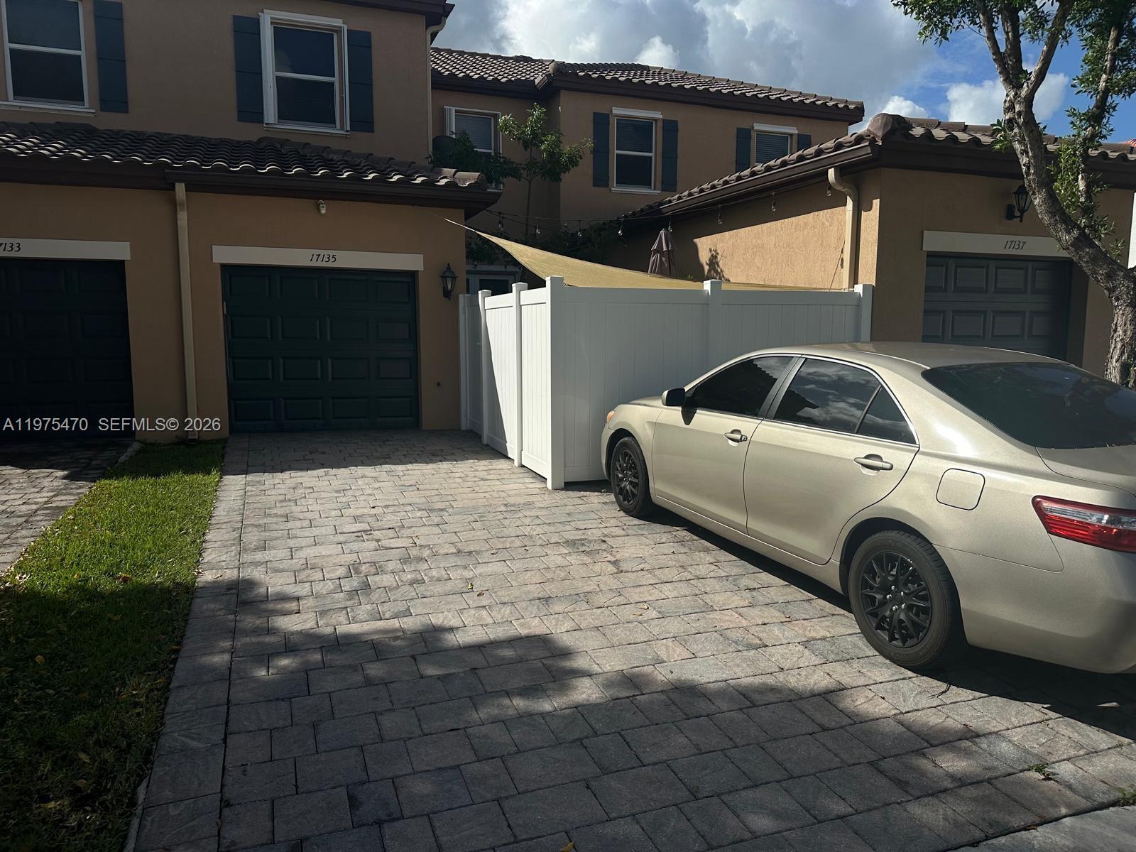 A beige sedan is parked on a paved driveway in front of a two-story townhouse — 17135 SW 96 ST, Miami FL 33196, MIAMI, FL