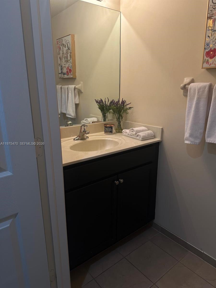A bathroom features a dark vanity with a light countertop, a mirror, and white towels — 17135 SW 96 ST, Miami FL 33196, MIAMI, FL