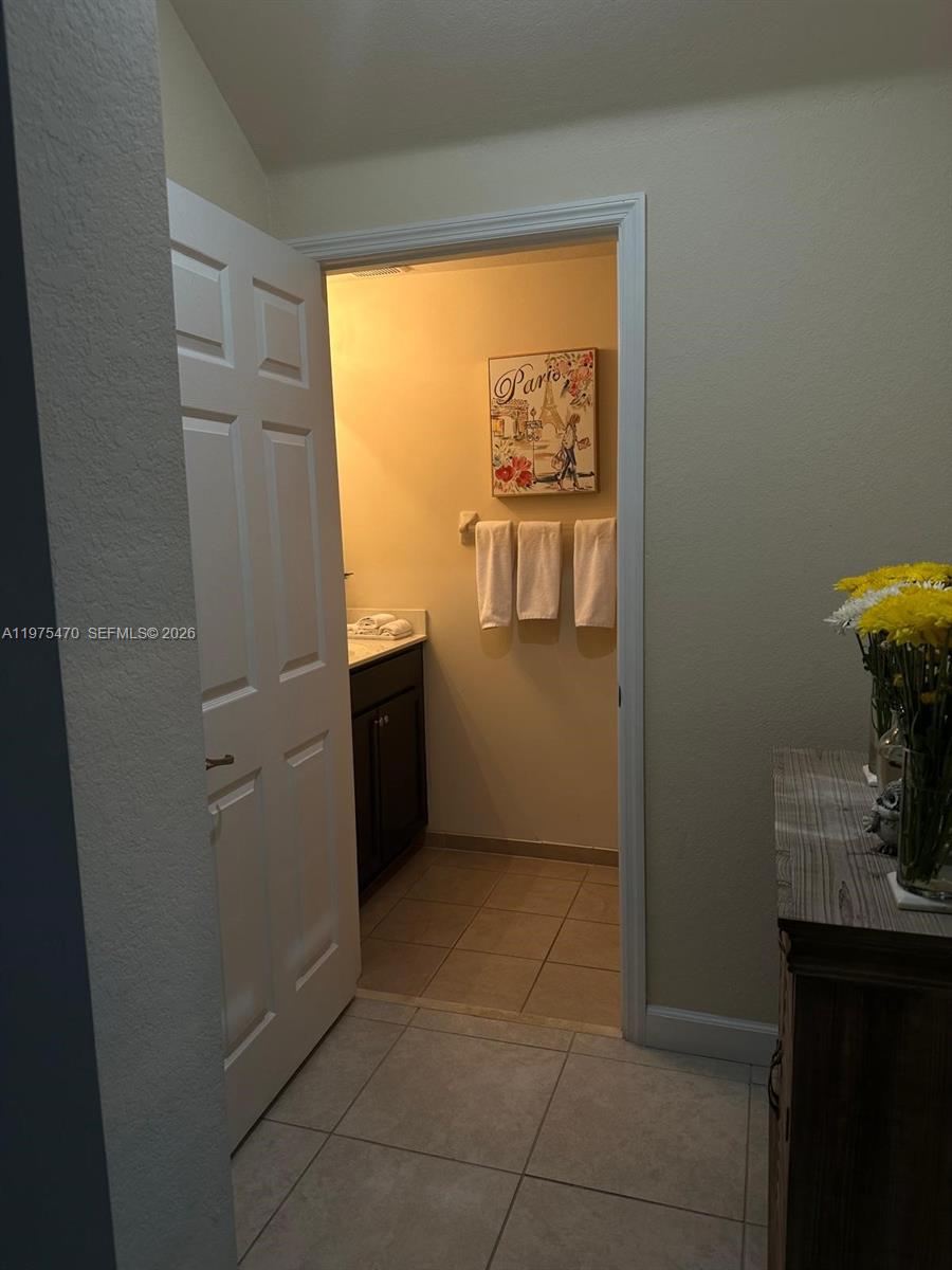 A doorway opens into a small bathroom with a vanity, tile flooring, and wall art — 17135 SW 96 ST, Miami FL 33196, MIAMI, FL