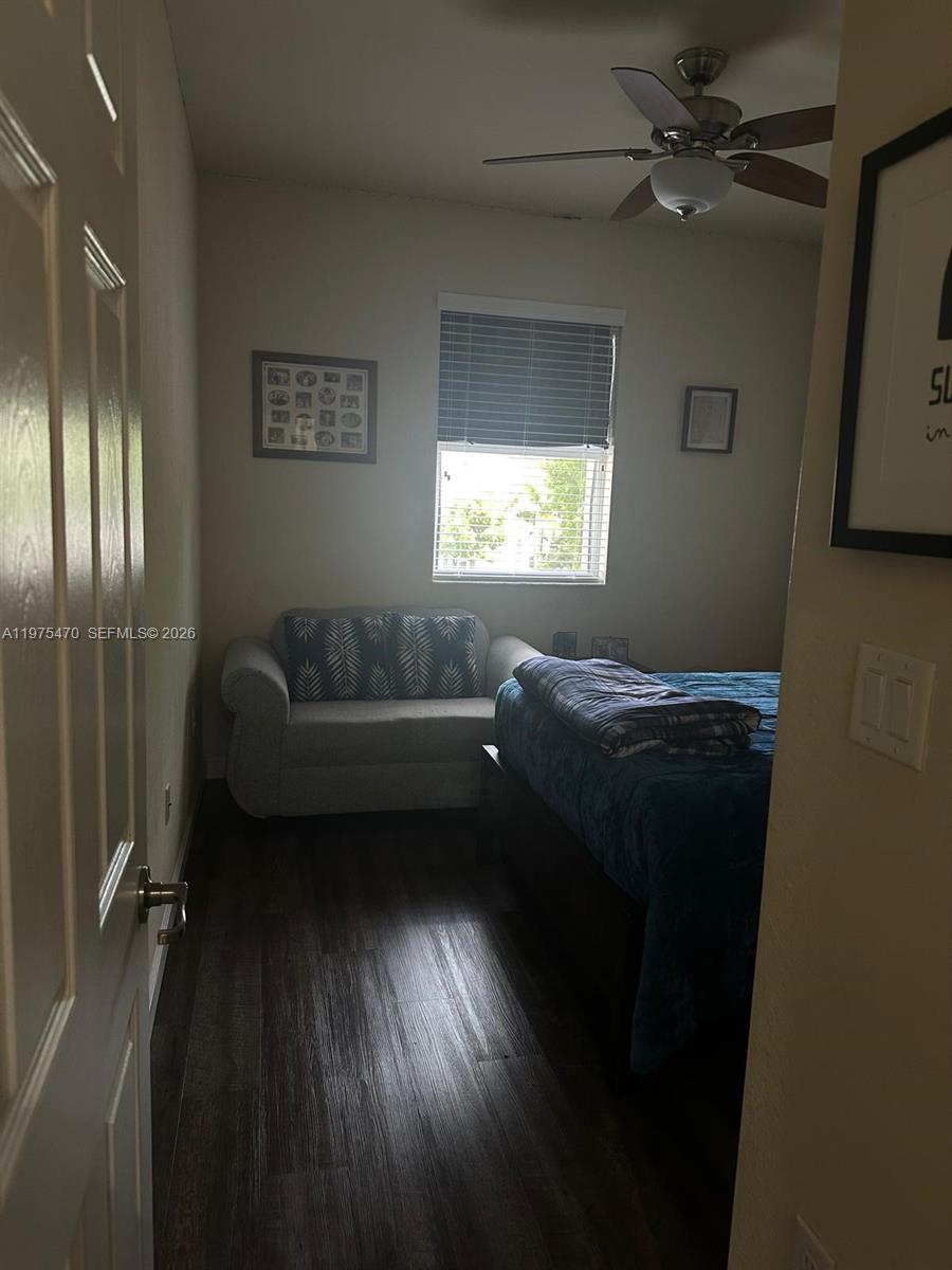 A bedroom features dark wood-look flooring, a bed, a small sofa, and a ceiling fan — 17135 SW 96 ST, Miami FL 33196, MIAMI, FL