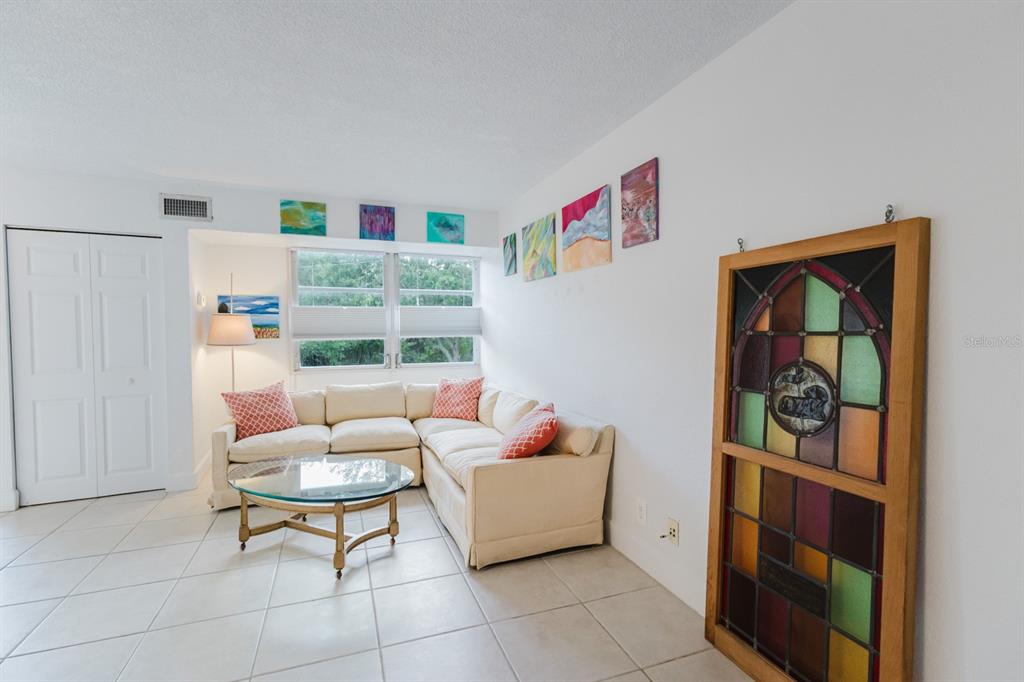 A living room with a white sectional sofa, tile floors, and a stained glass window frame — 3315 58TH AVENUE S UNIT 222, ST PETERSBURG, FL