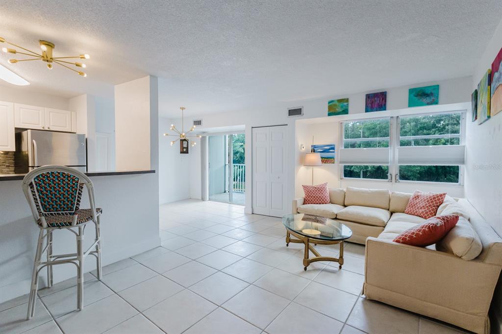 A living room with tile floors, a beige sectional sofa, and an open kitchen area — 3315 58TH AVENUE S UNIT 222, ST PETERSBURG, FL