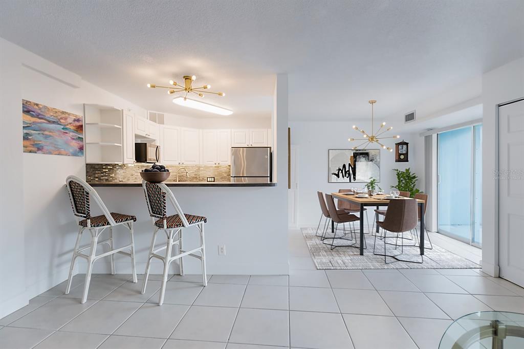 A kitchen with white cabinets and a breakfast bar overlooks a dining area with tile floors — 3315 58TH AVENUE S UNIT 222, ST PETERSBURG, FL