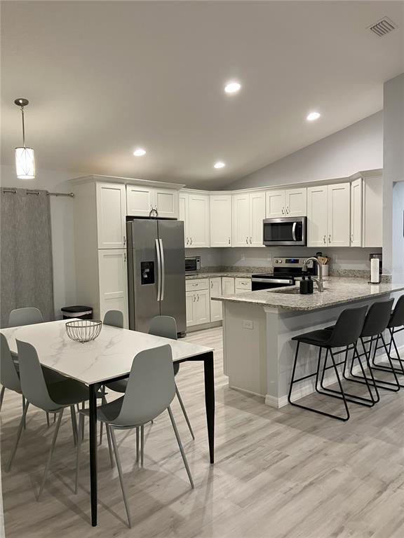 A kitchen with white cabinets, granite countertops, and a dining area with a marble table — 5415 SW 153RD PLACE ROAD, OCALA, FL