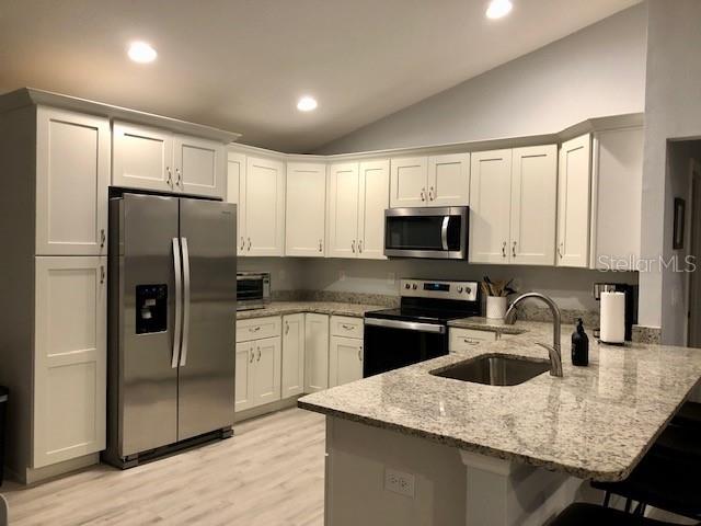 A kitchen features white cabinets, stainless steel appliances, and a granite-topped island — 5415 SW 153RD PLACE ROAD, OCALA, FL