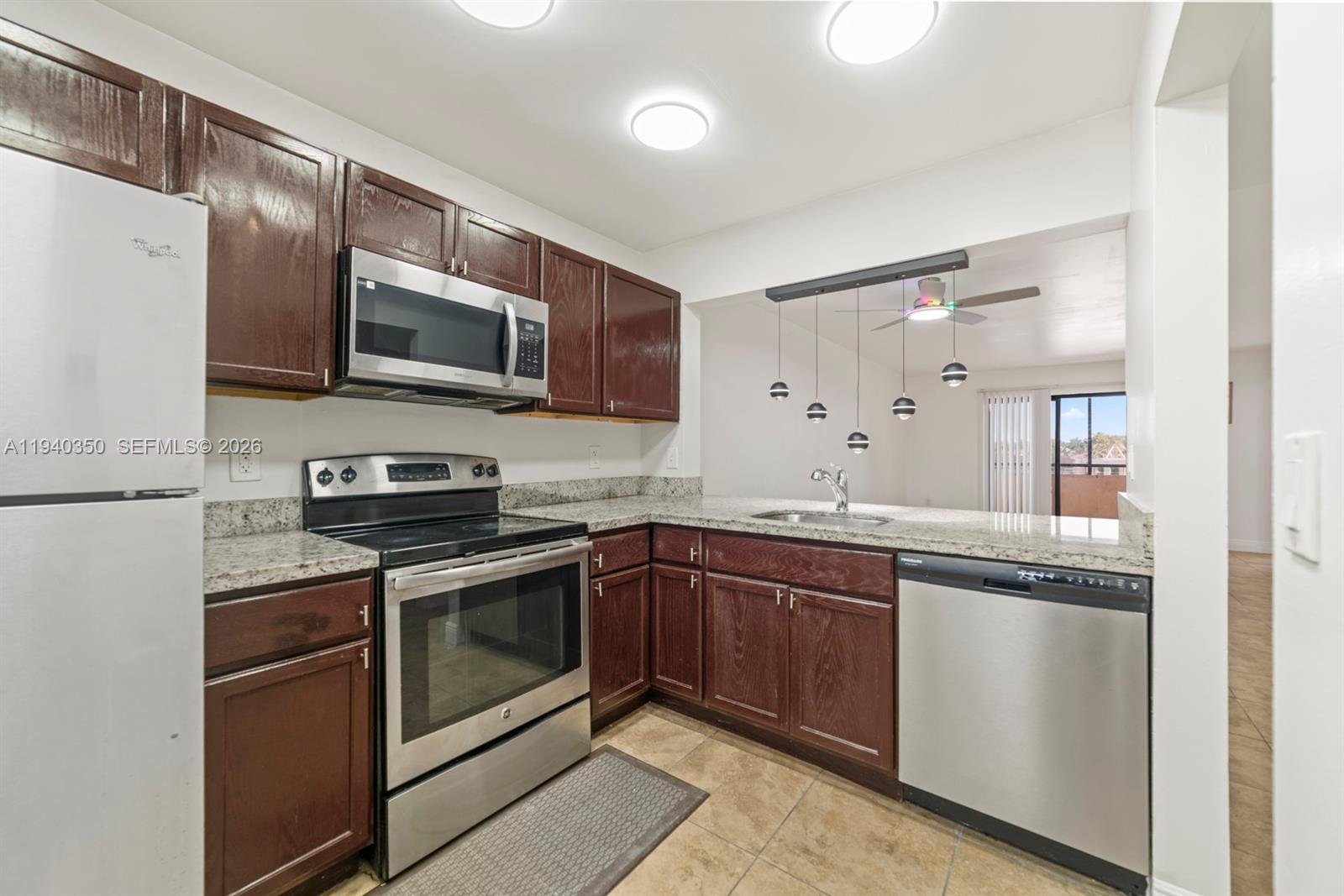 A kitchen features dark wood cabinets, stainless steel appliances, and granite countertops — 880 NE 207th Ter # 10, Miami FL 33179, MIAMI, FL