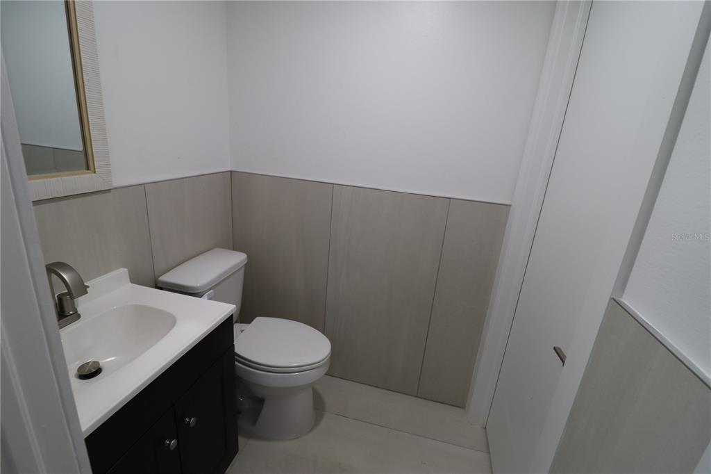 A small bathroom features a dark vanity, a white toilet, and light-colored wall tile — 1225 TAMIAMI TRAIL UNIT A8, PORT CHARLOTTE, FL