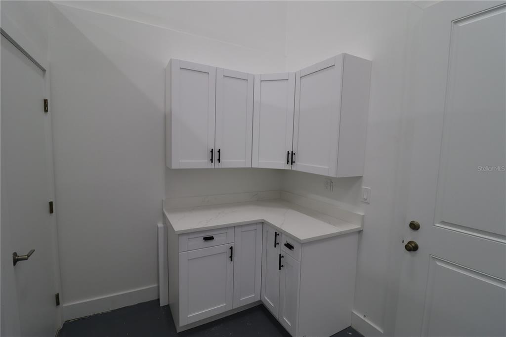 A laundry room features white shaker cabinets, a marble-look countertop, and dark hardware — 1225 TAMIAMI TRAIL UNIT A8, PORT CHARLOTTE, FL