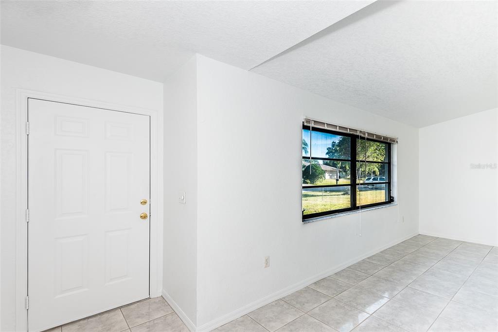 A room with white walls, tiled floors, a white door, and a window with blinds — 838 JARVIS STREET, PORT CHARLOTTE, FL