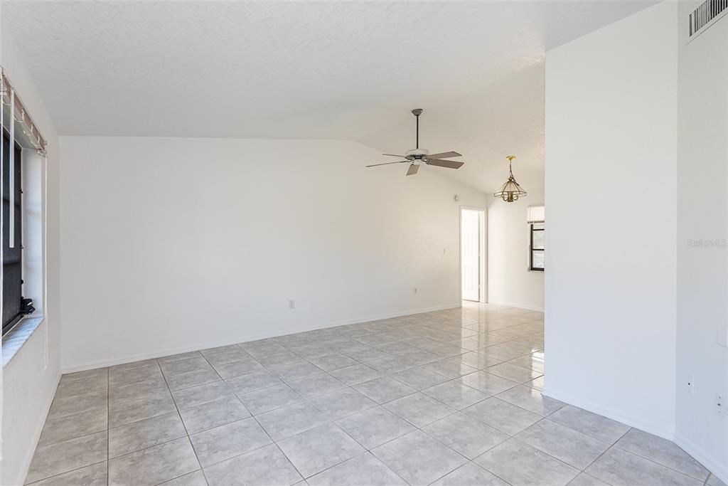 An empty room with white walls, gray tile flooring, and a ceiling fan — 838 JARVIS STREET, PORT CHARLOTTE, FL