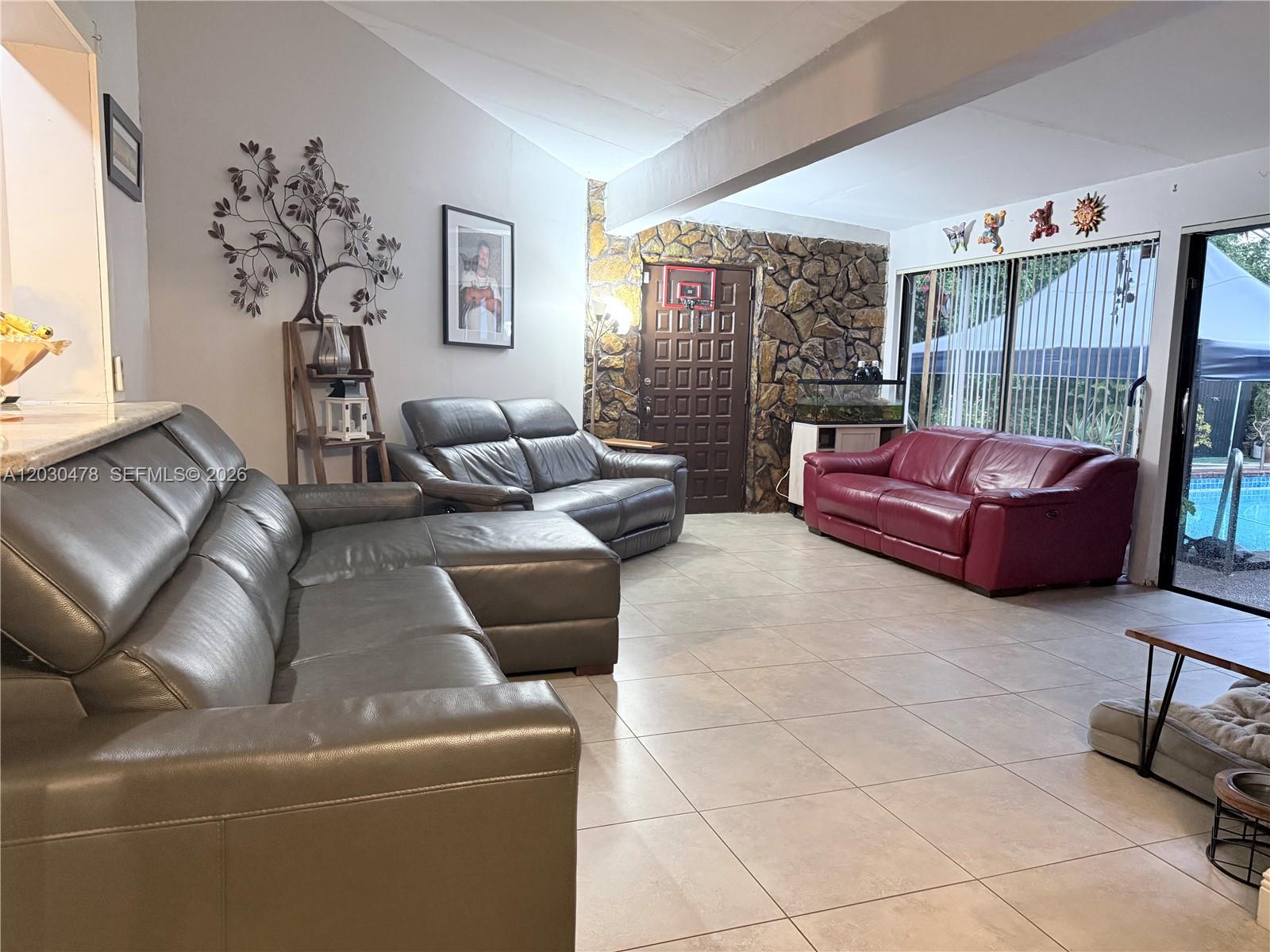 A living room features tile floors, a stone accent wall, and three leather sofas — 18240 NE 8th Ave, North Miami Beach FL 33162, NORTH MIAMI BEACH, FL