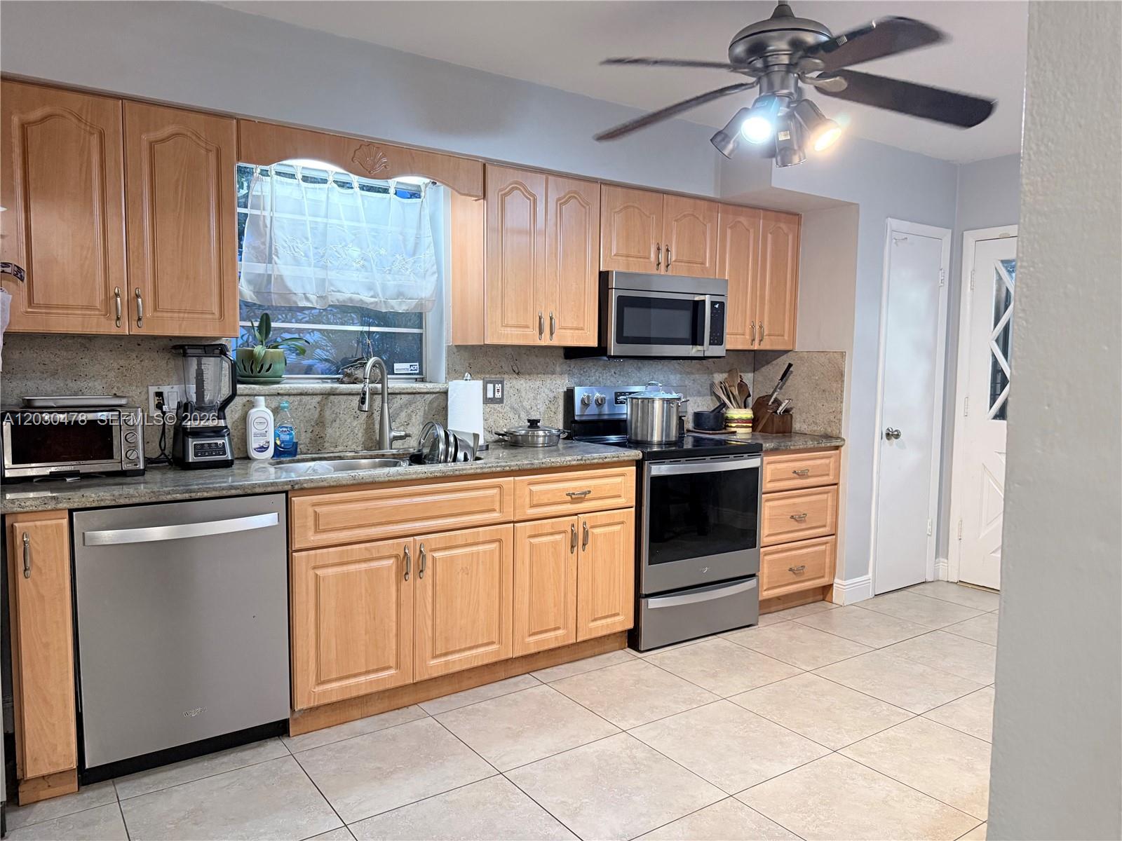 A kitchen features light wood cabinets, stainless steel appliances, and granite countertops — 18240 NE 8th Ave, North Miami Beach FL 33162, NORTH MIAMI BEACH, FL