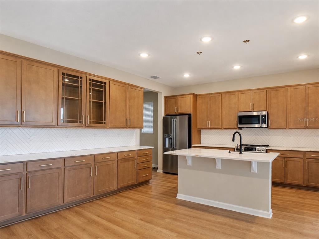 A kitchen features wood cabinets, white countertops, a center island, and a herringbone tile backsplash — 1028 SUGARWOOD STREET, DAVENPORT, FL