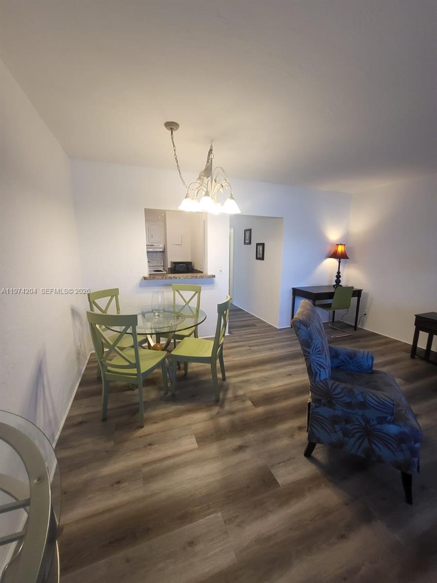 A dining area with a glass table and green chairs sits near a kitchen pass-through — 600 Layne Blvd # 216, Hallandale Beach FL 33009, HALLANDALE BEACH, FL