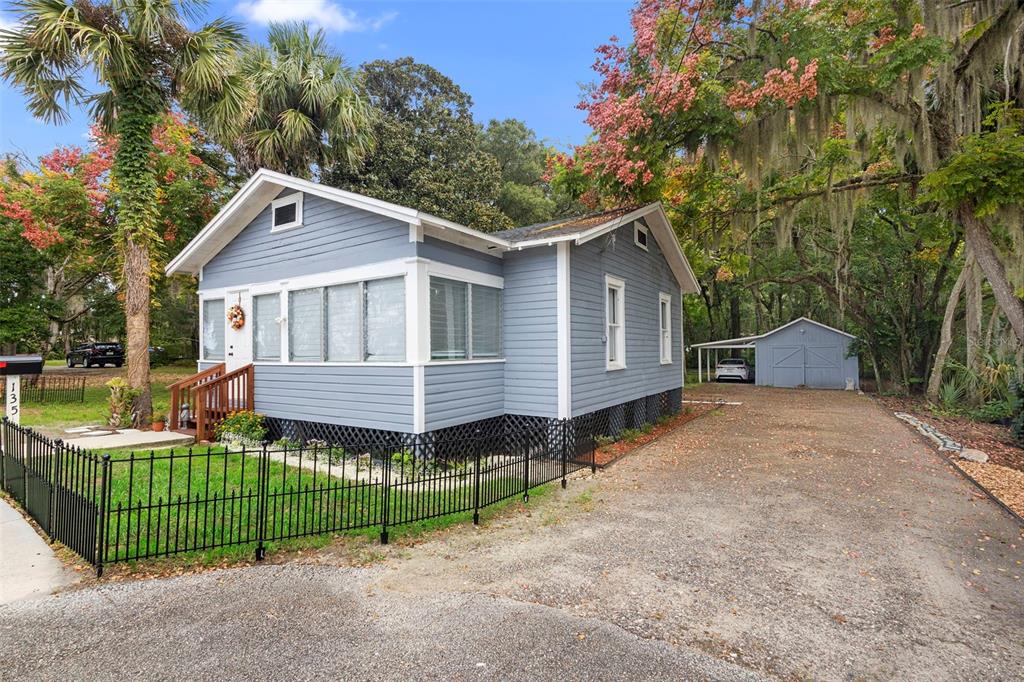 A blue, single-story house with a front porch, metal fence, and a detached garage — 135 S ARLINGTON AVENUE, DELAND, FL