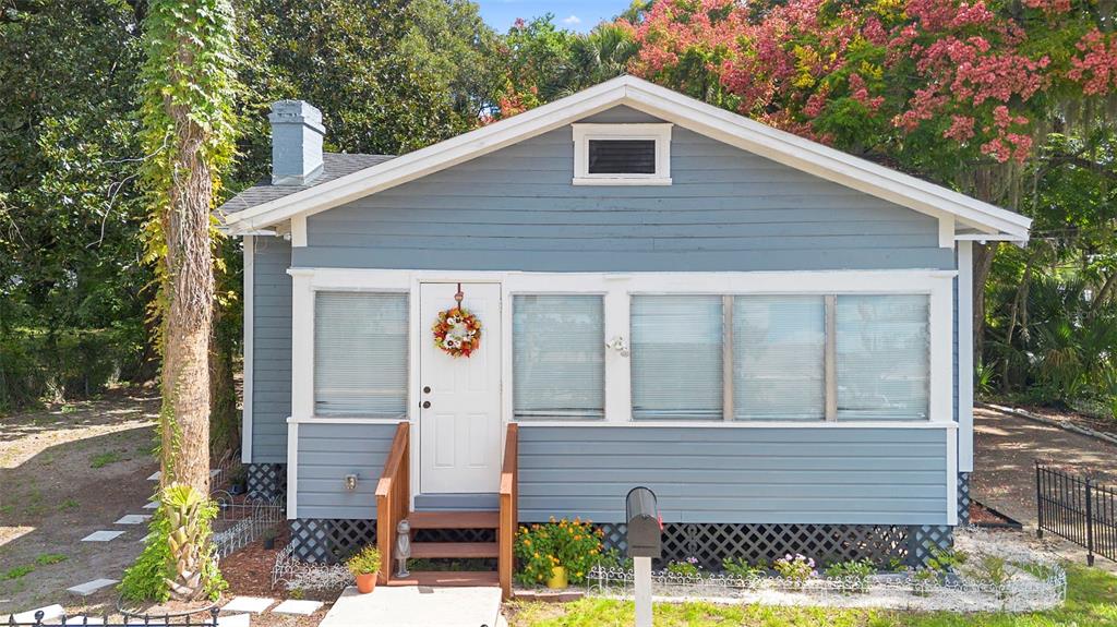A blue, single-story house with a front porch, white trim, and a lattice foundation — 135 S ARLINGTON AVENUE, DELAND, FL