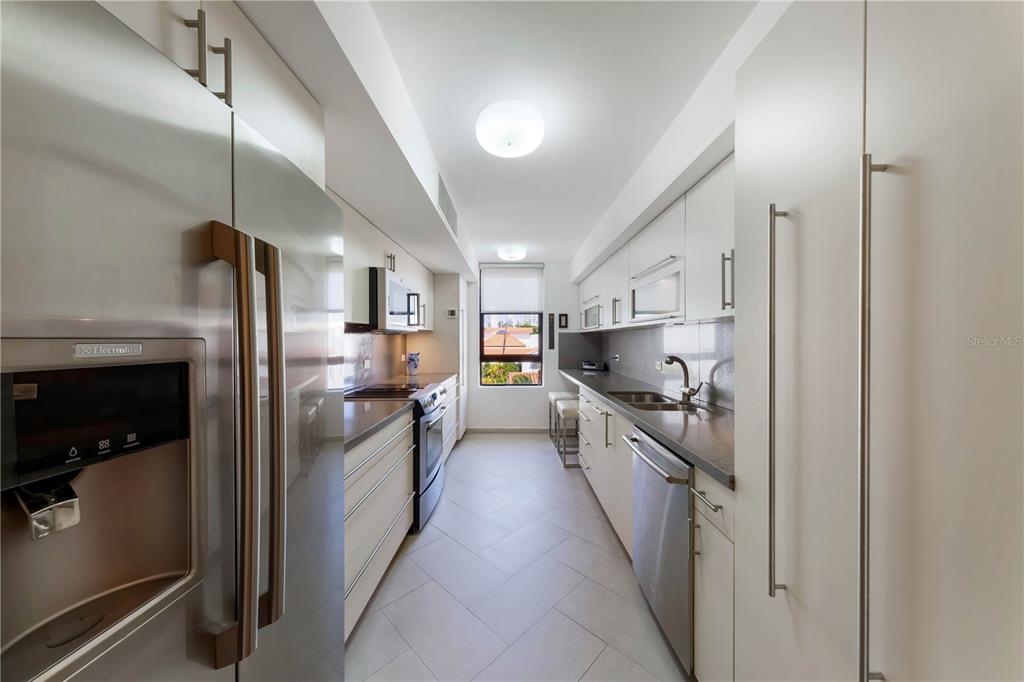 A galley kitchen features white cabinetry, stainless steel appliances, and light-colored tile flooring — 552 WAYMOUTH STREET UNIT C, SAN JUAN, PR
