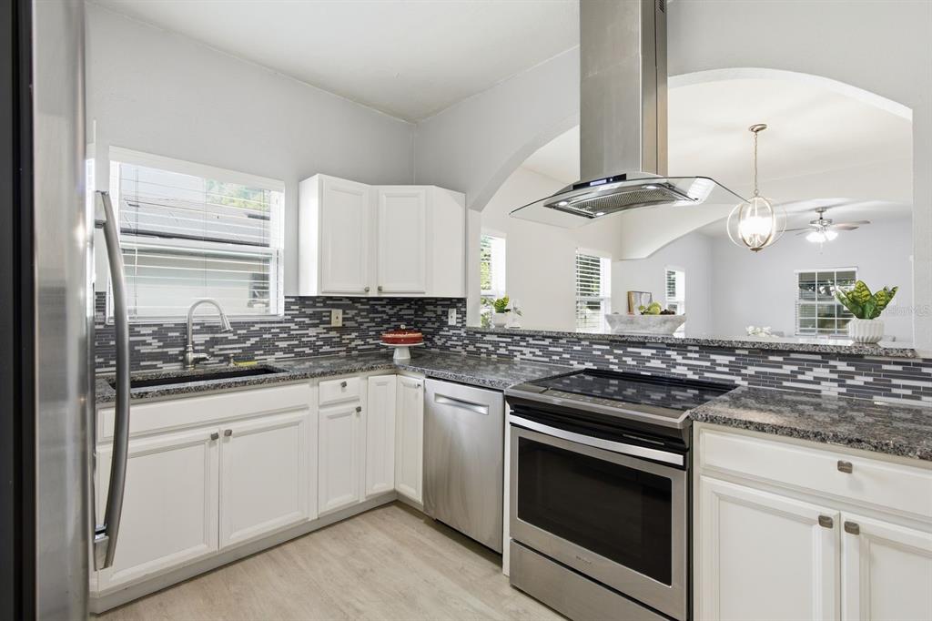 A kitchen with white cabinets, granite countertops, stainless steel appliances, and a tiled backsplash — 2815 N TALIAFERRO AVENUE, TAMPA, FL