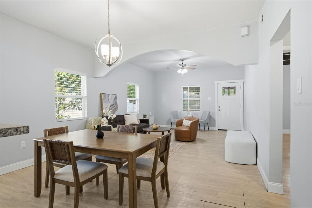 A dining area and living room with light wood flooring, an arched ceiling, and white walls — 2815 N TALIAFERRO AVENUE, TAMPA, FL