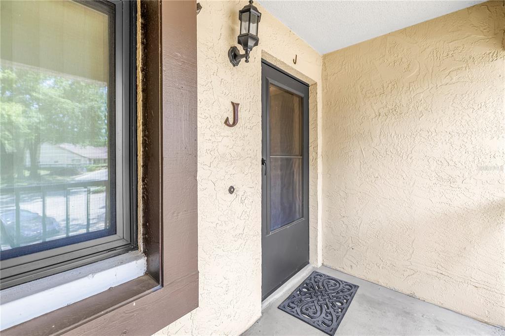 An exterior view of a residential entryway featuring a door labeled with the letter J — 3600 MAGNOLIA RIDGE CIRCLE UNIT 1224, PALM HARBOR, FL