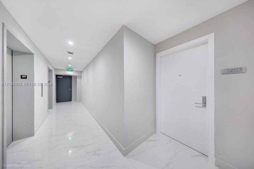 A white hallway features marble-style flooring, a white door labeled 1403, and an elevator — 700 NE 24 St # 1403, Miami FL 33137, MIAMI, FL