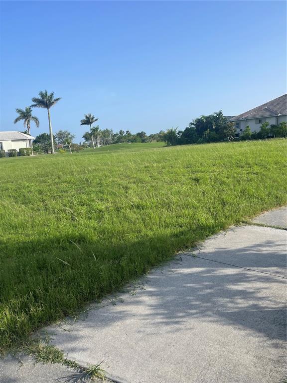 A vacant, grassy residential lot sits adjacent to a concrete sidewalk and neighboring houses — 3701 BORDEAUX DRIVE, PUNTA GORDA, FL