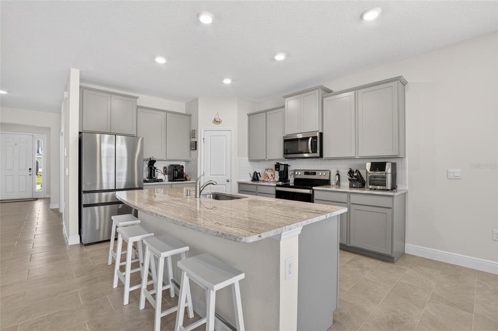 A kitchen features gray cabinets, stainless steel appliances, and light-colored granite countertops — 152 BRIGHT IBIS AVENUE, APOLLO BEACH, FL