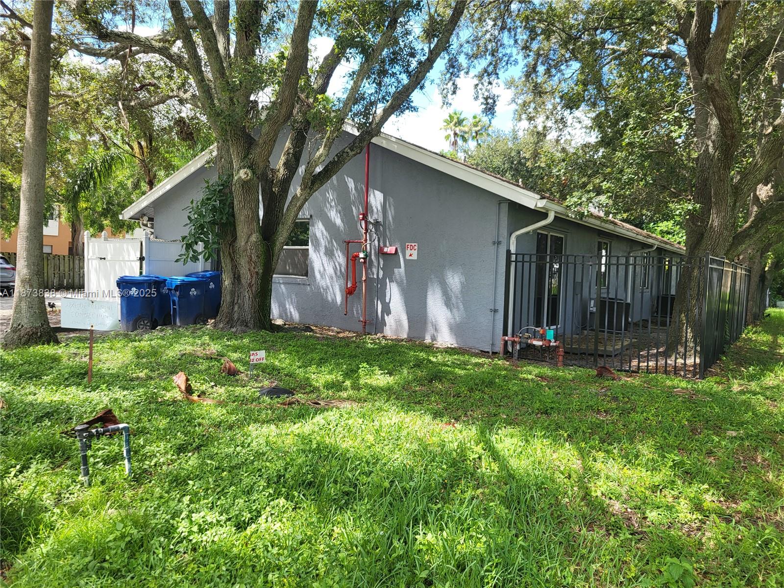 The exterior of a gray house features a fire department connection pipe and a fenced yard — 3621 NW 90th Ter, Sunrise FL 33351, SUNRISE, FL