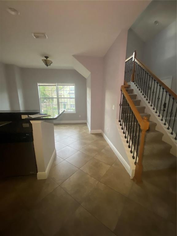 A tiled entryway features a staircase with a wooden handrail and a nearby kitchen counter — 3721 S LAKE ORLANDO PARKWAY UNIT 2, ORLANDO, FL