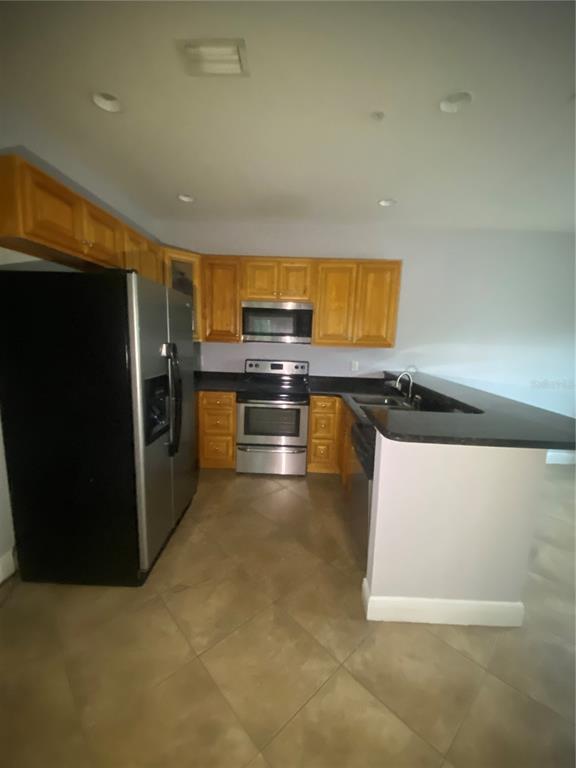A kitchen features light wood cabinets, stainless steel appliances, and a black countertop peninsula — 3721 S LAKE ORLANDO PARKWAY UNIT 2, ORLANDO, FL