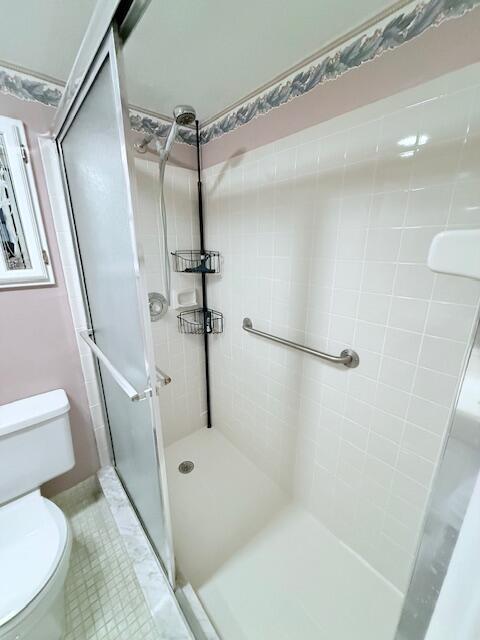 A walk-in shower with a glass door, grab bar, and corner caddy in a bathroom — 1027 Berkshire B, Deerfield Beach FL 33442, DEERFIELD BEACH, FL