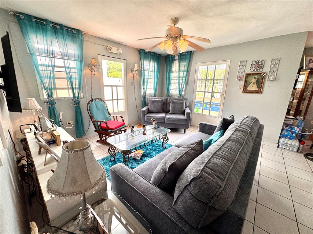 A living room features gray sofas, a glass coffee table, and teal curtains over windows — Carretera #970 BO. MAIZALES, NAGUABO, PR