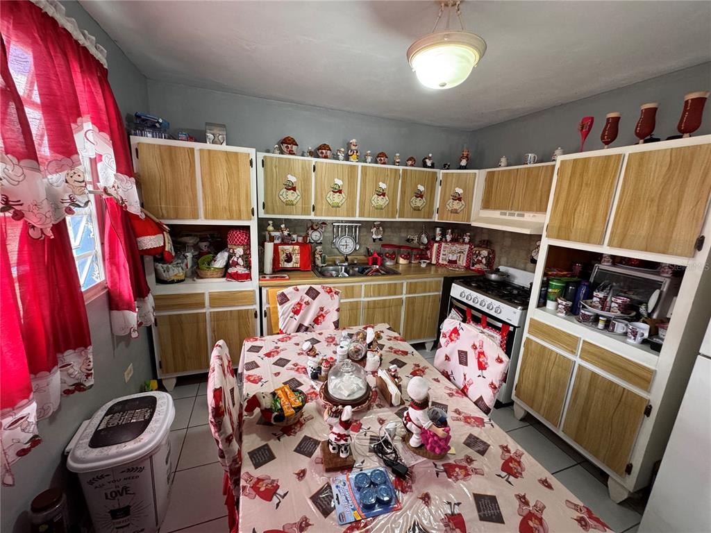 A kitchen features wood-trimmed cabinets, a dining table with patterned linens, and chef-themed decor — Carretera #970 BO. MAIZALES, NAGUABO, PR
