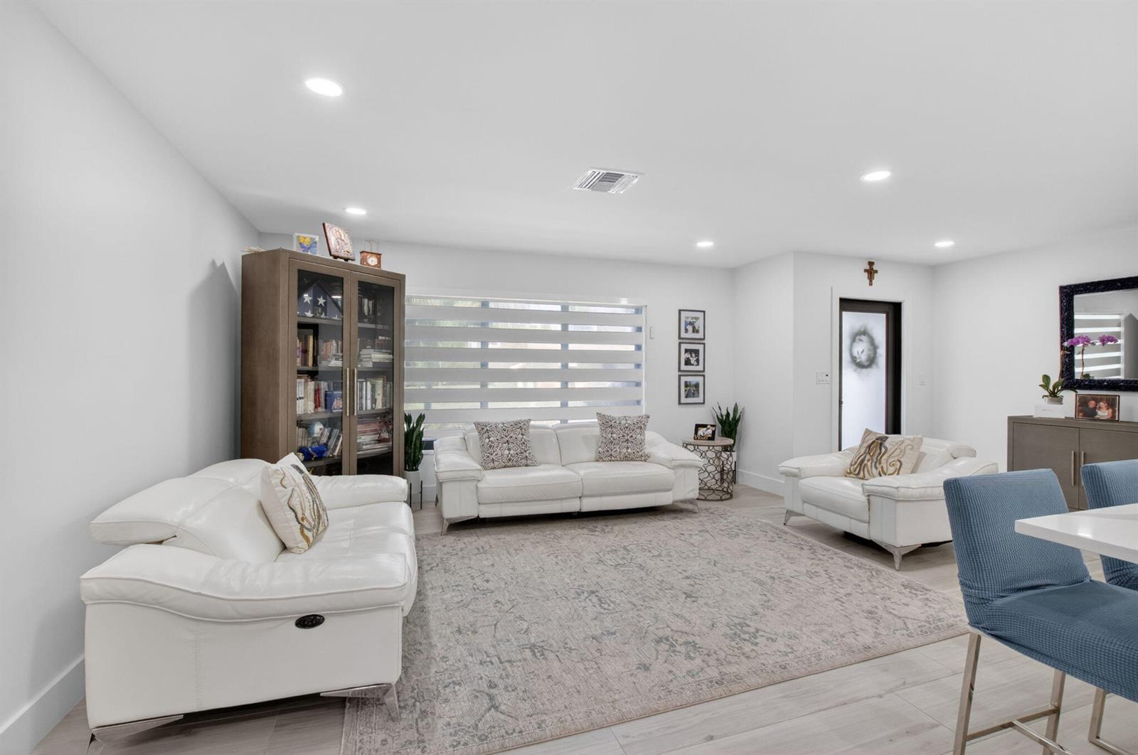 A bright living room features white leather sofas, a patterned area rug, and a bookshelf — 658 NW 7th Avenue, Boca Raton FL 33486, BOCA RATON, FL
