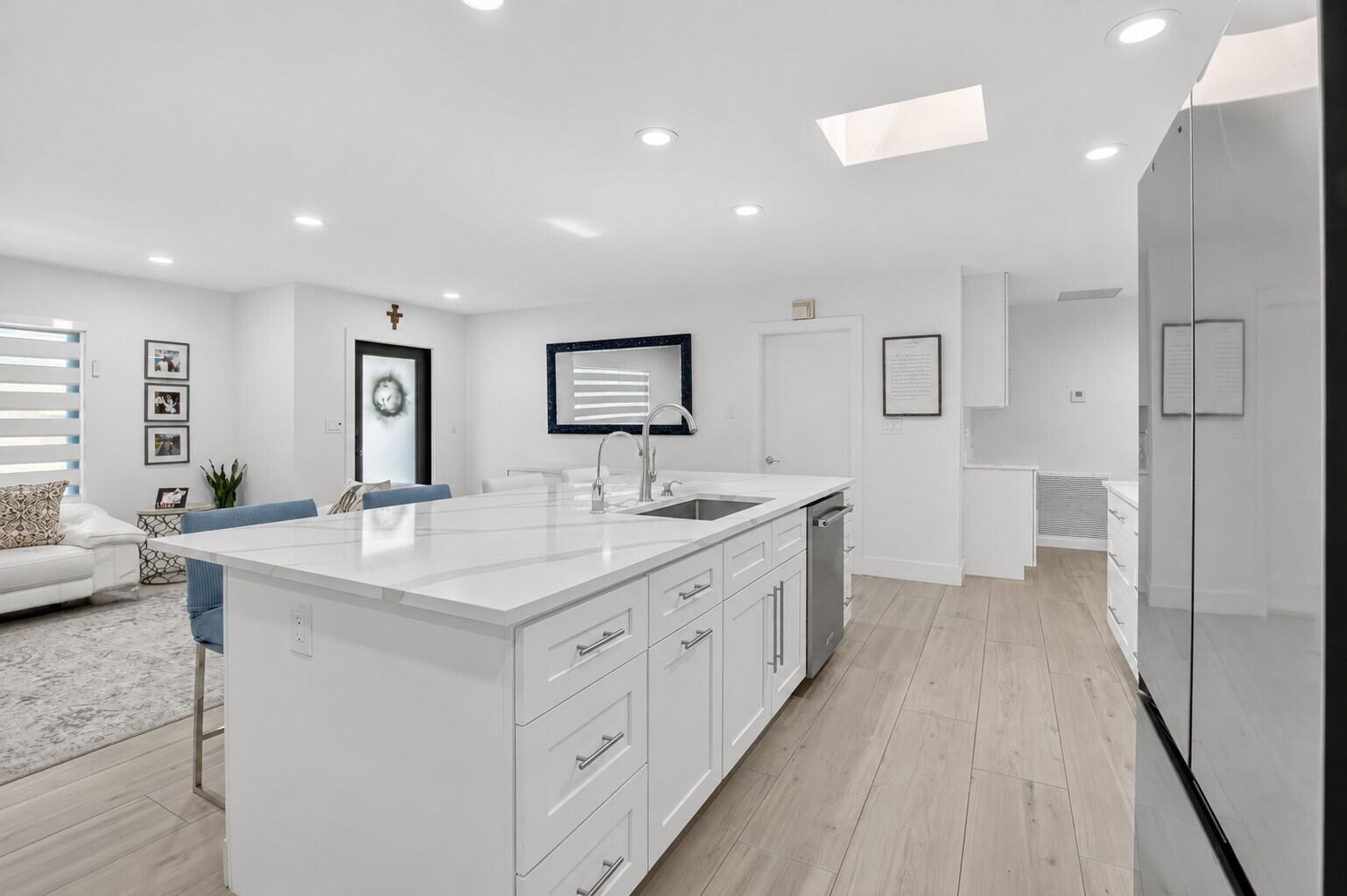 A modern white kitchen island with quartz countertops sits in an open-concept room with light flooring — 658 NW 7th Avenue, Boca Raton FL 33486, BOCA RATON, FL