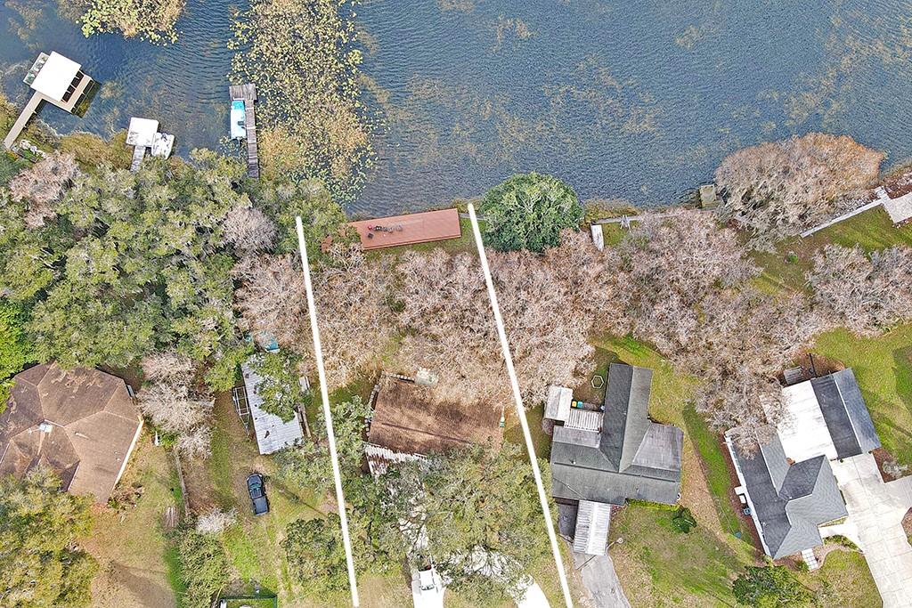 An aerial view shows a lakefront property with a house, trees, and a wooden dock — 426 ELLA AVENUE, INVERNESS, FL